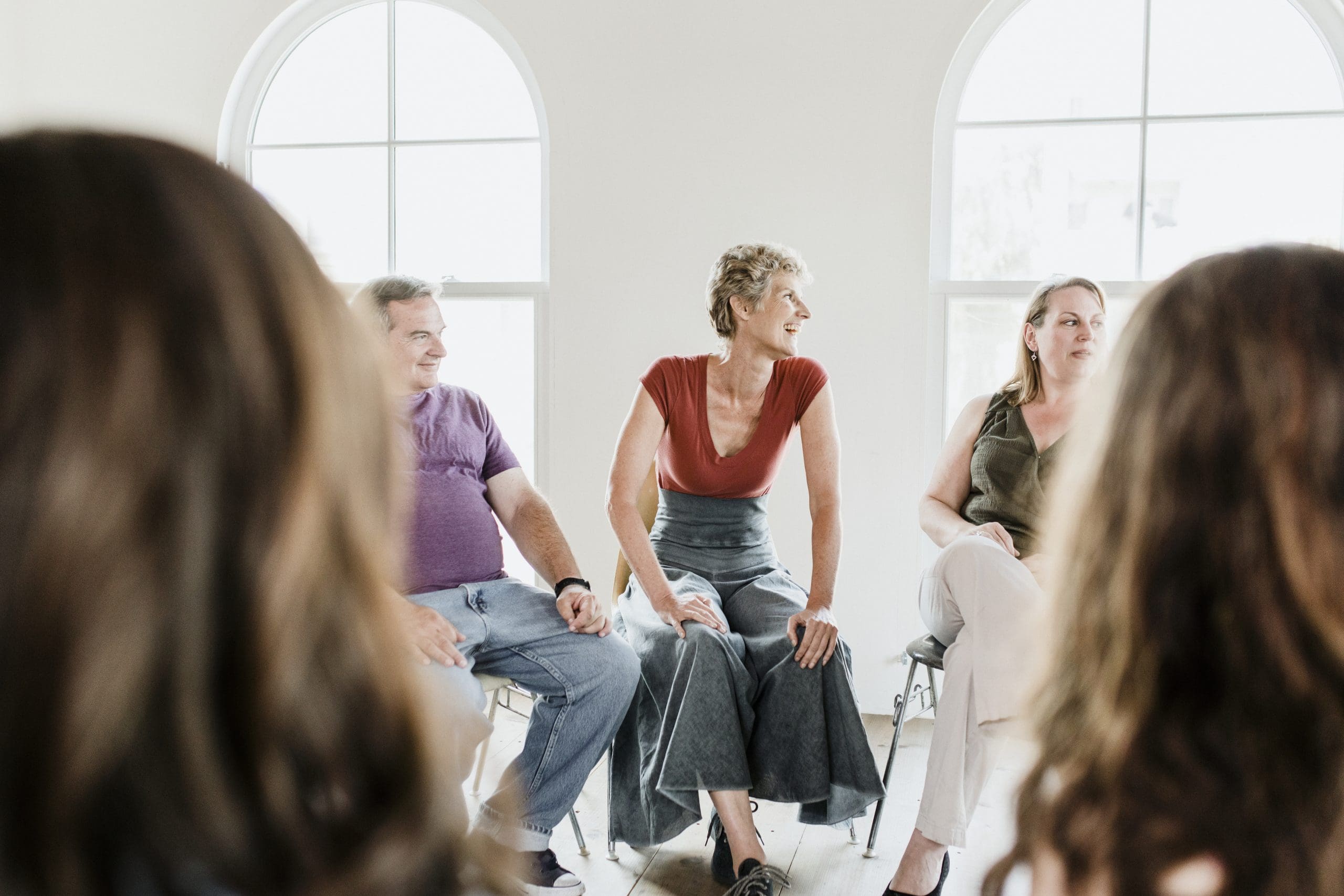 A diverse group of adults sit together listening during a peer support session.